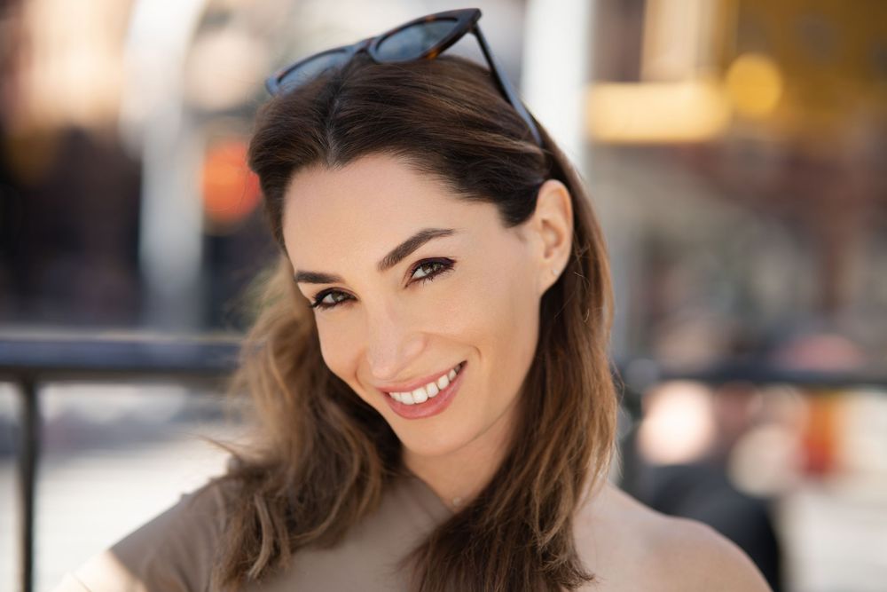 Outdoor portrait with sunglasses pushed up and natural smile.