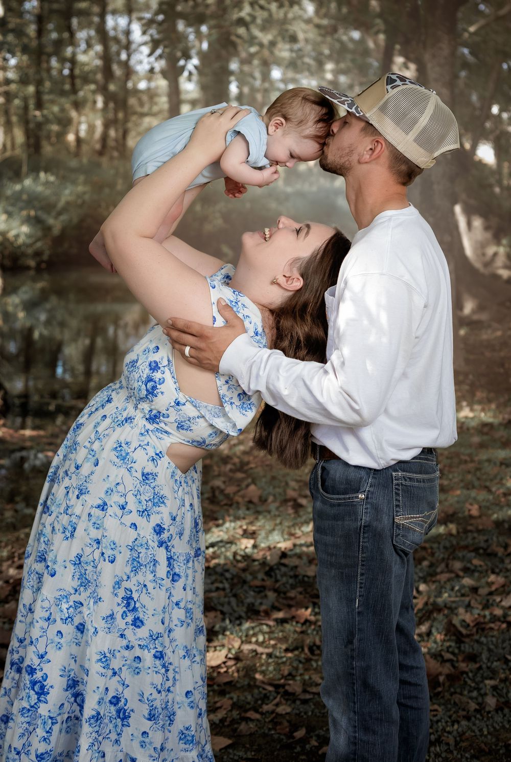 Outdoor family portraits in Lincoln, Alabama featuring parents playing with their baby in a wooded setting