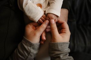 Close-up of tiny baby hands and fingers against dark background.