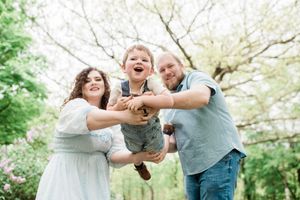 Family playing and laughing together under blooming spring trees.