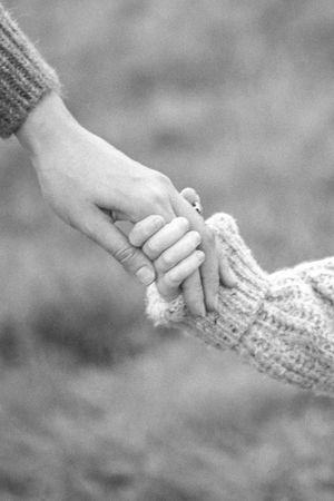 Two hands holding a knitted fabric in a gentle close-up black and white shot.