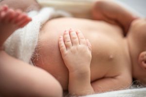 Close-up of a tiny baby's hand against a soft white background.