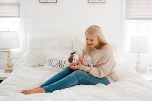 Cozy maternity photo session on white bed with natural window light.