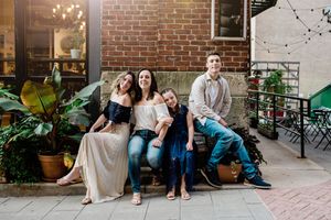Family sitting together on brick steps in a casual outdoor photoshoot.