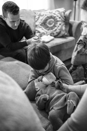 Black and white image of family members sitting together on a couch.