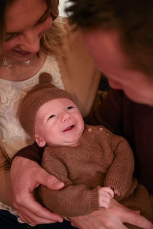 Baby wearing brown knit sweater smiling during a tender family moment.