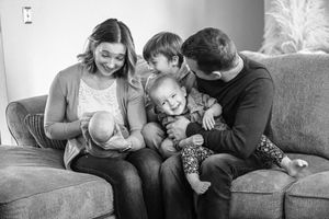 Family sitting together on a gray couch sharing intimate moments.