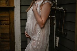A white dress photographed against rustic siding in moody lighting.