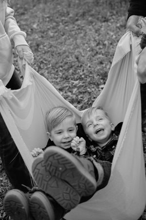Children playing and laughing together in a white hammock outdoors.