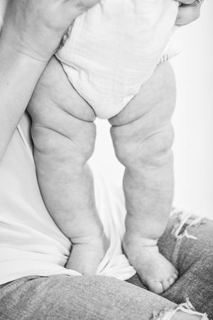 Close-up of baby's chubby legs and feet resting on denim fabric.