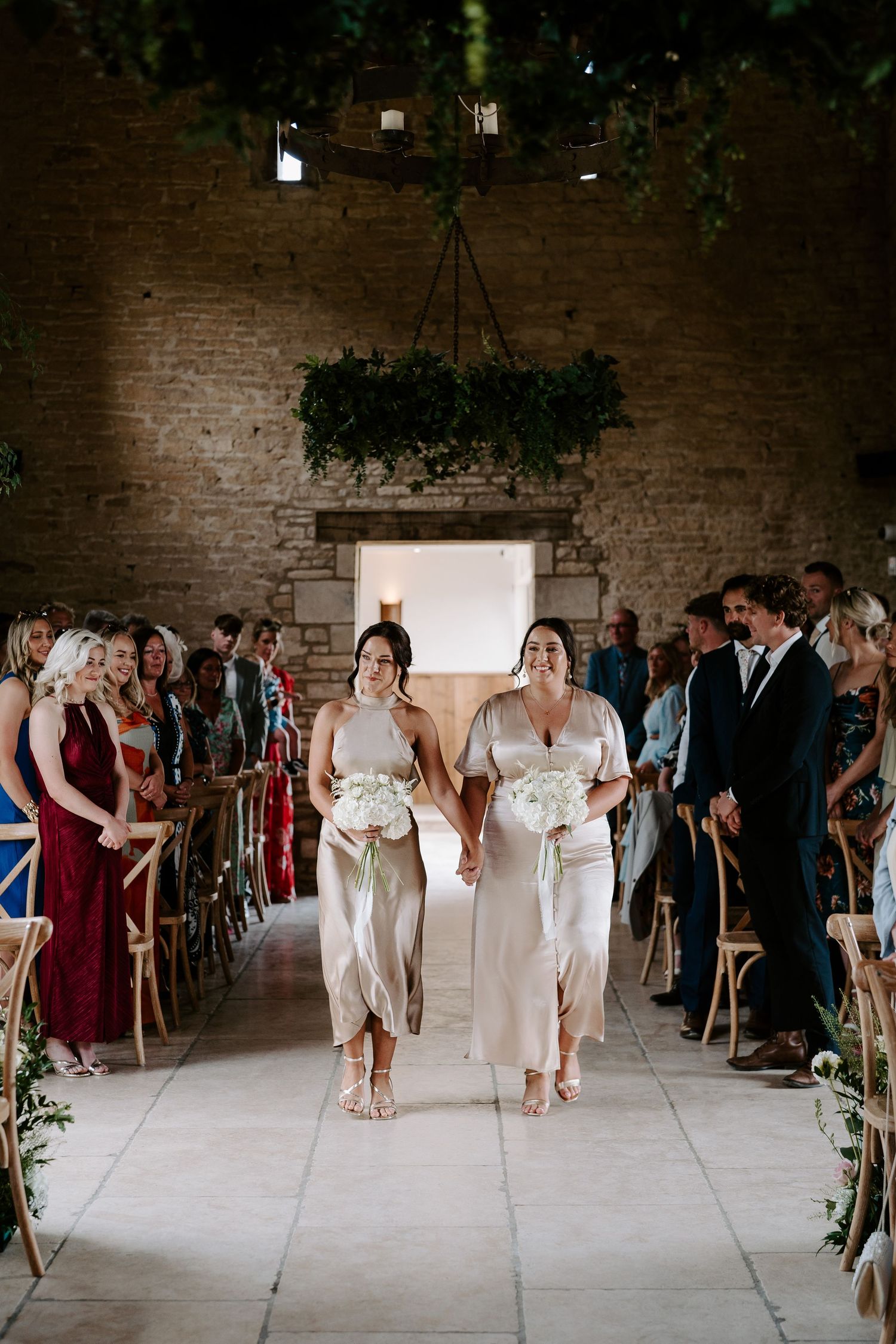 bridesmaids walking down aisle during wedding ceremony at yardspace old gore in cirencester