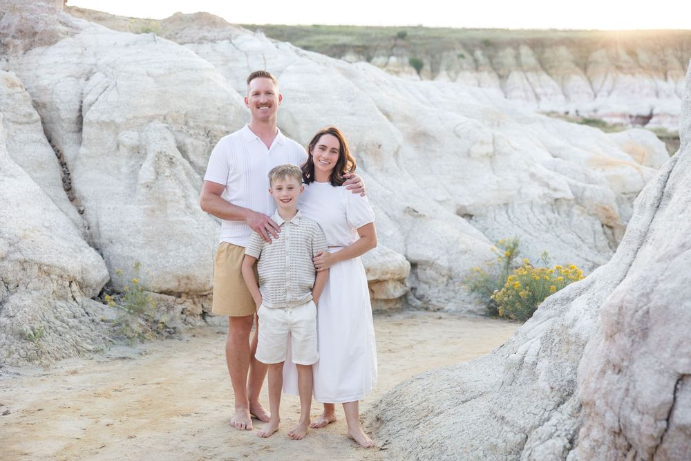 A couple stands together in front of white chalk cliffs during a sunny outdoor photo session.