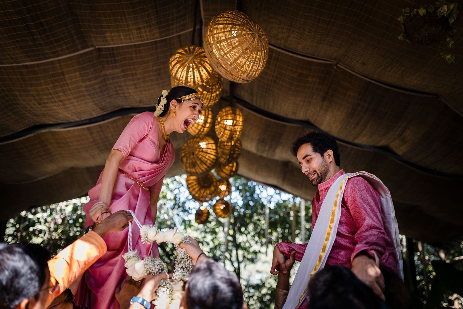 A festive celebration under hanging lanterns with people in pink traditional attire.