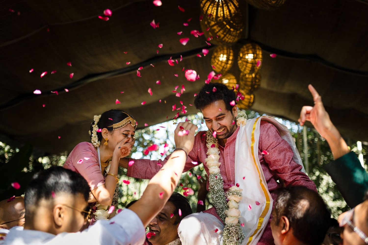 Joyous celebration with flower petals being thrown during an Indian wedding ceremony.
