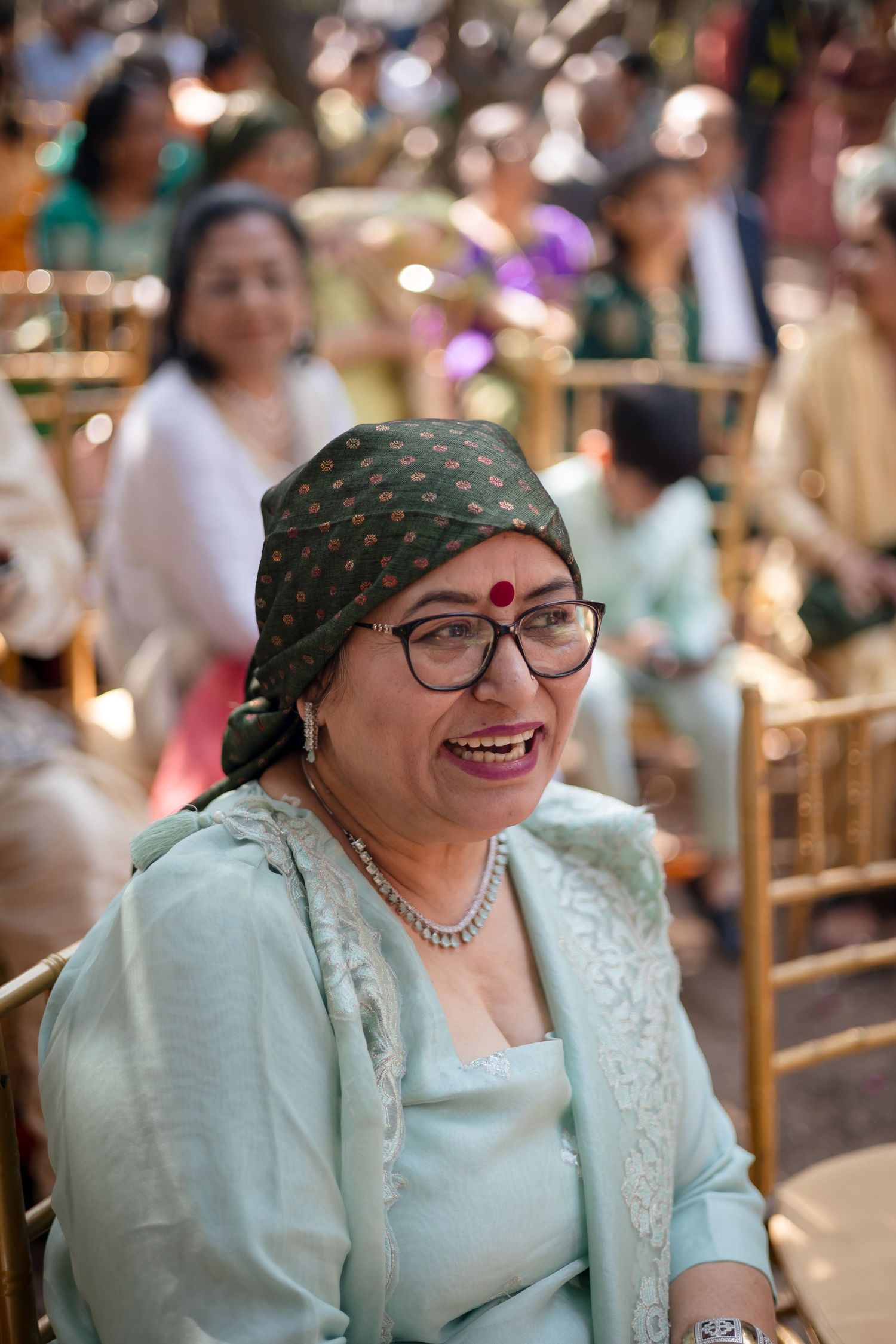 A guest wearing a mint green outfit and headscarf enjoys the outdoor celebration.