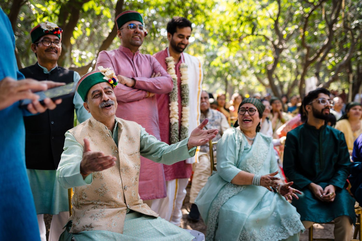 Wedding guests in traditional attire enjoying themselves at an outdoor gathering.