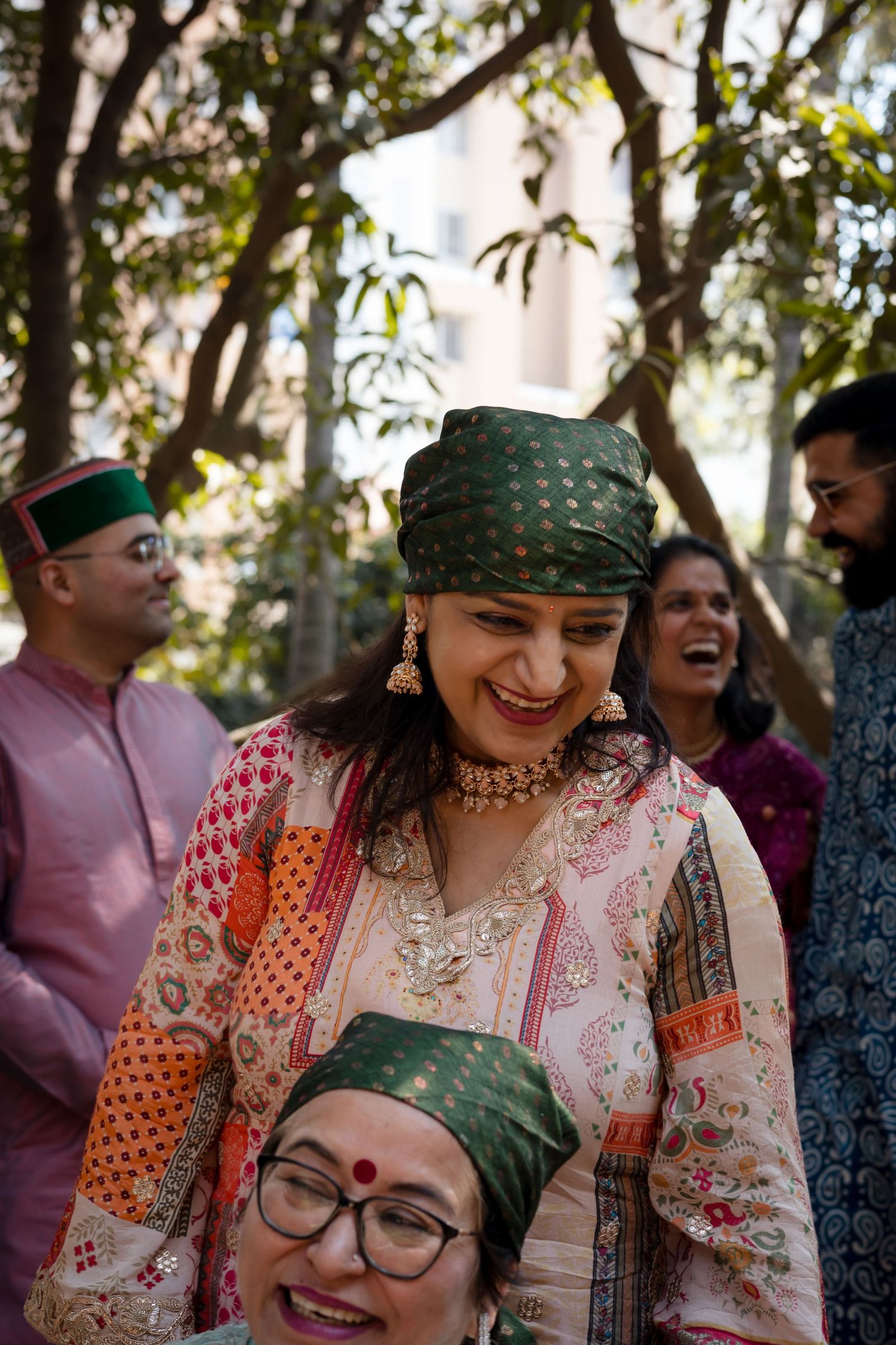 Guests in traditional clothing sharing laughter at an outdoor celebration.
