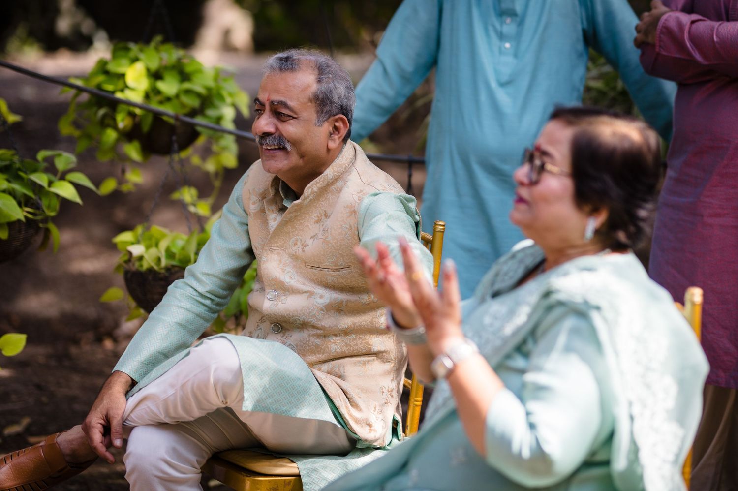 Elderly guests enjoying conversation during an outdoor event while seated in chairs.