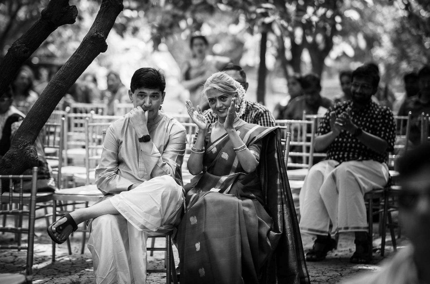 Guests sitting in chairs having an animated conversation at an outdoor gathering.