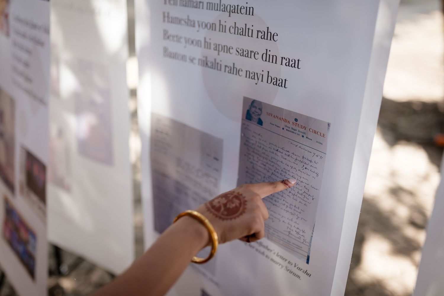A finger points to text in a document under natural sunlight.