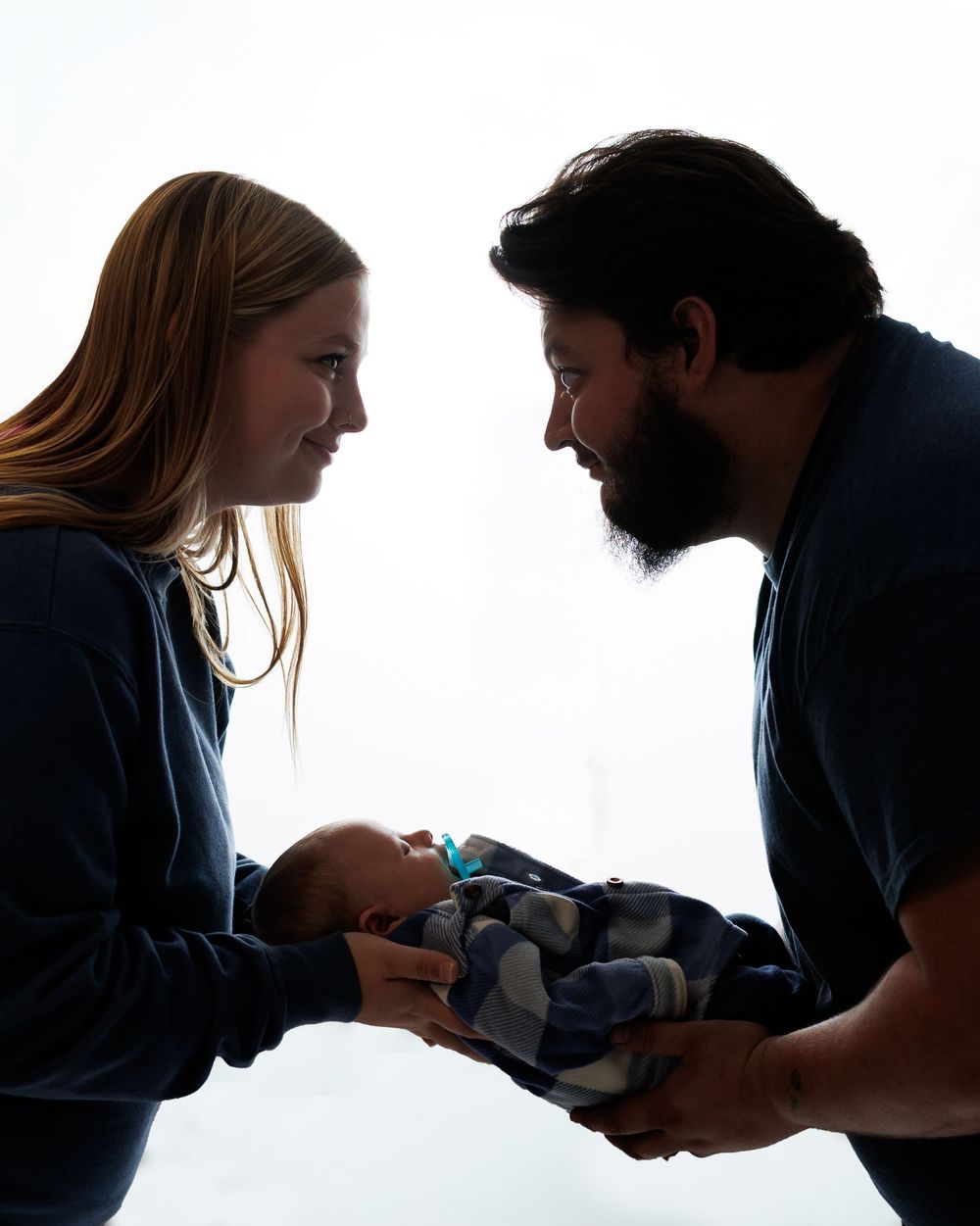 Silhouetted figures in a series of tender moments with a baby against a white background.