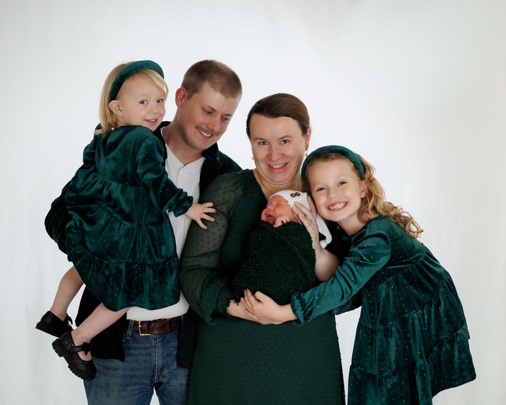 A group wearing matching green jackets and jeans pose together in a casual portrait series.