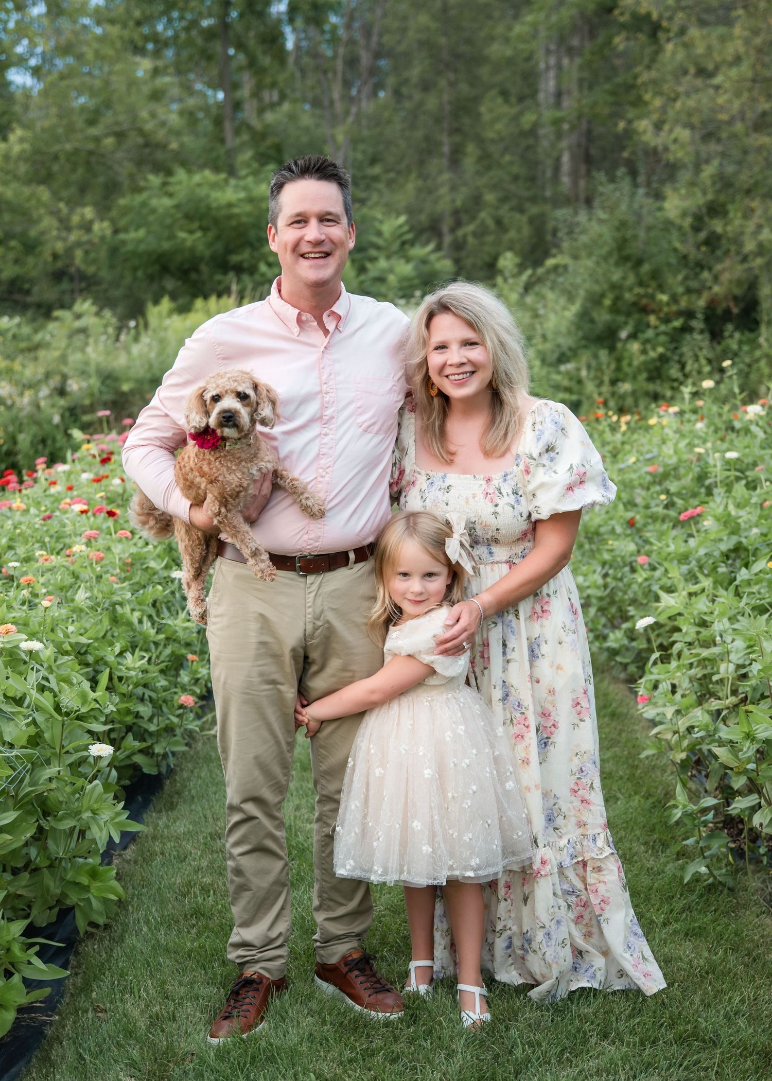 A family poses together in a garden path lined with colorful flowers at sunset.