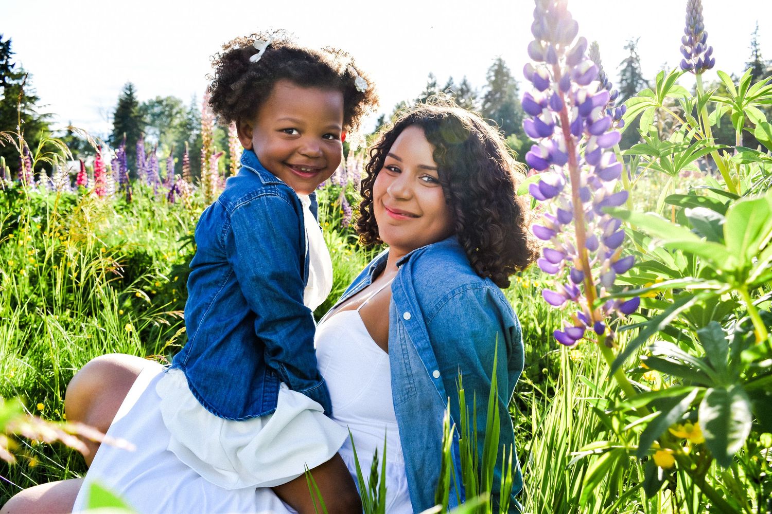 Mother and daughter smiling among lupines in full bloom—playful family portraits in a wildflower field in Kent, WA.