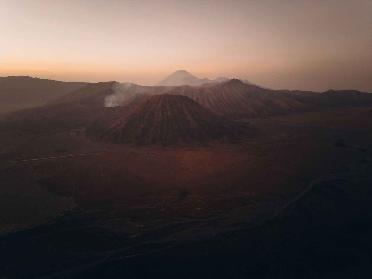 Aerial view of Mount Bromo volcano in East Java Indonesia at sunrise with misty peaks and desert landscape.