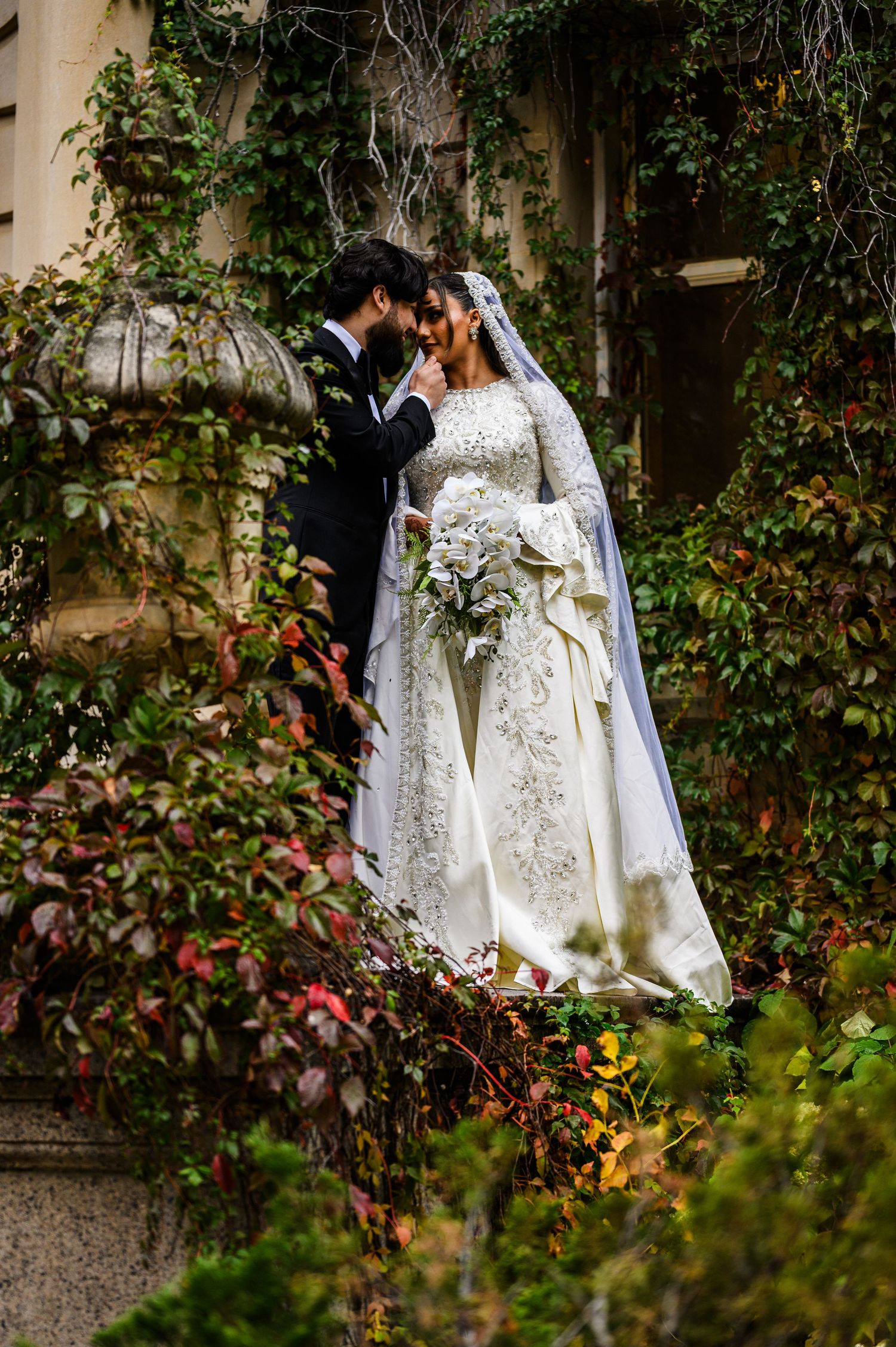 A bride in a white gown stands in front of illuminated curved archways creating a dramatic nighttime wedding portrait.