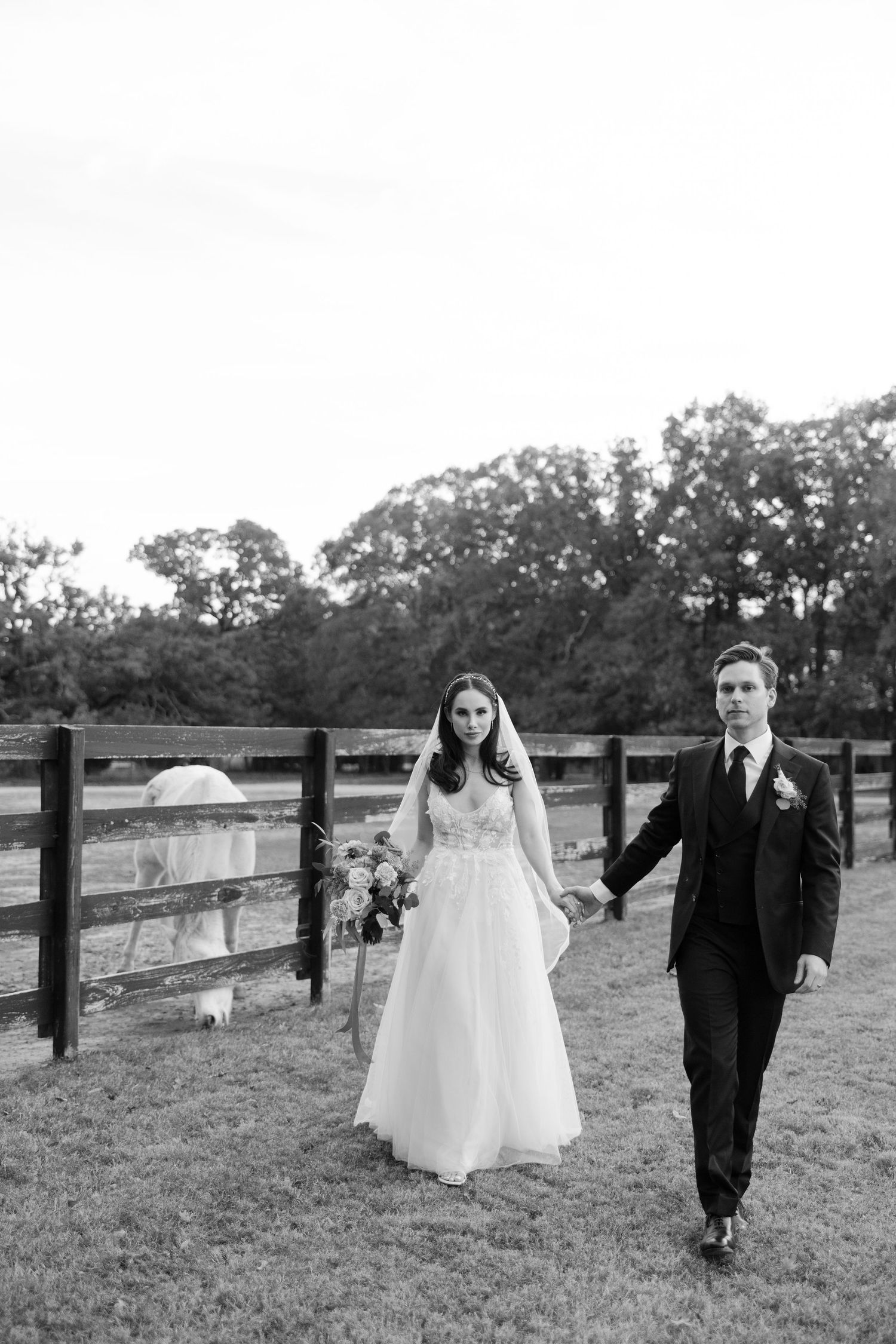 A side profile view of a bride wearing a delicate veil and embellished headpiece in black and white.