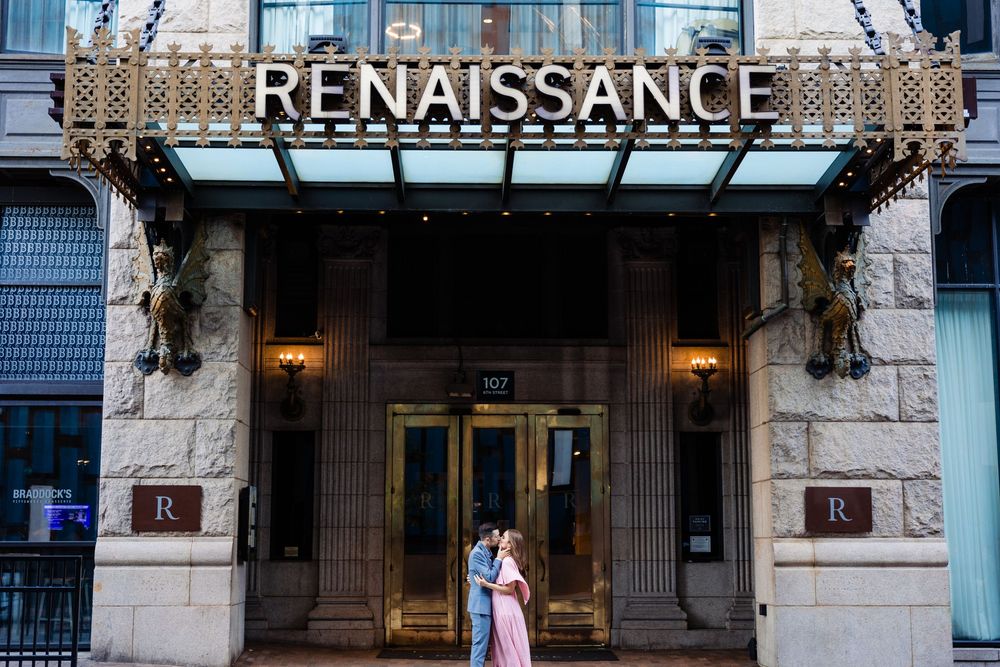Couple embracing under the Renaissance Hotel illuminated entrance canopy in an urban setting.