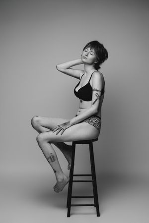 Black and white artistic photo series showing graceful poses on a wooden stool against a minimalist studio backdrop.