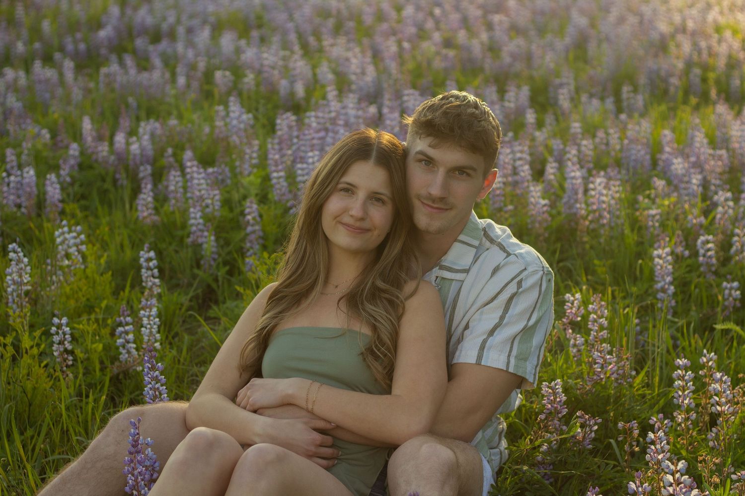 A couple plays and spins in a flower and grass field during their engagement photos in Flushing, Michigan.
