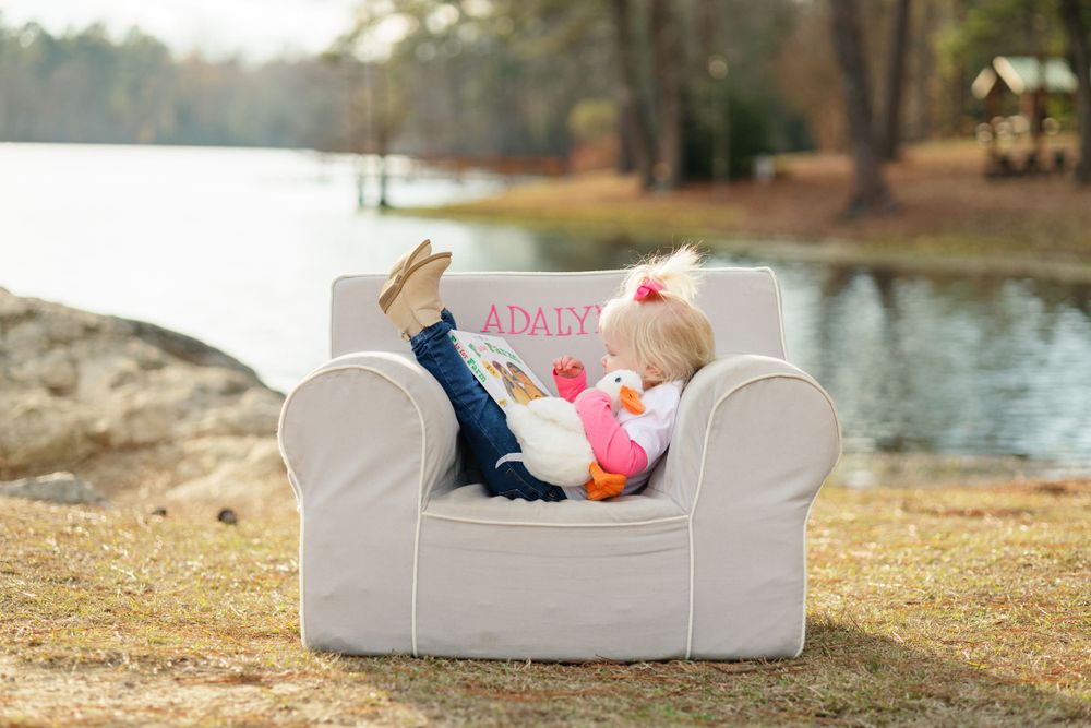 Small child relaxing in white armchair by lakeside.