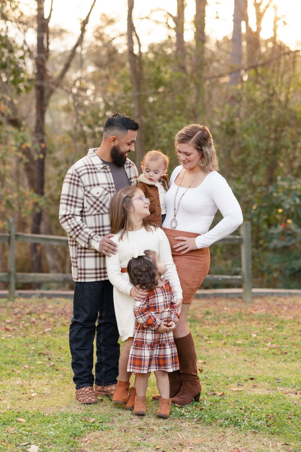 Family gathering outdoors in autumn with fall foliage in background.