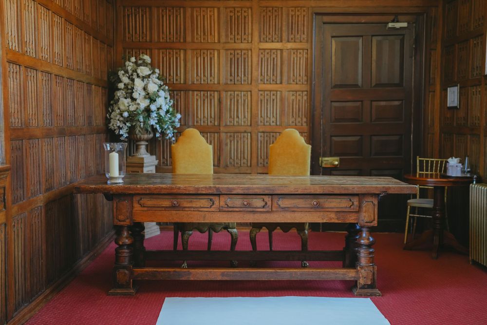 Interior view of a grand library with dark wood paneling and red upholstered seating.