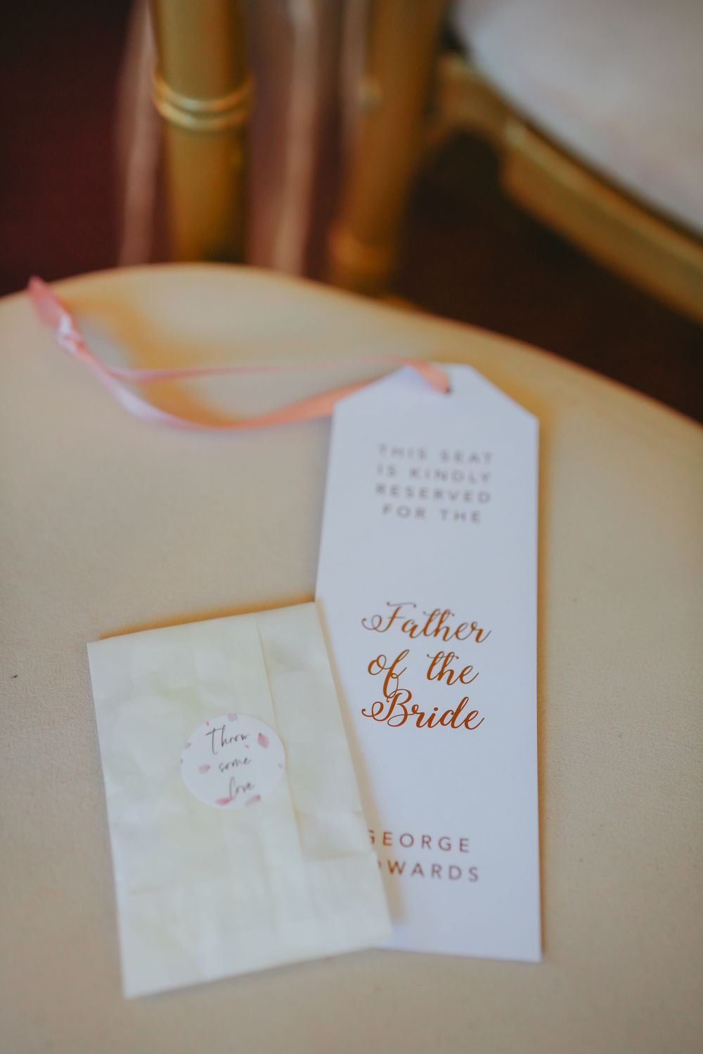 Close-up view of elegant white name cards with rose gold script lettering for a wedding event.