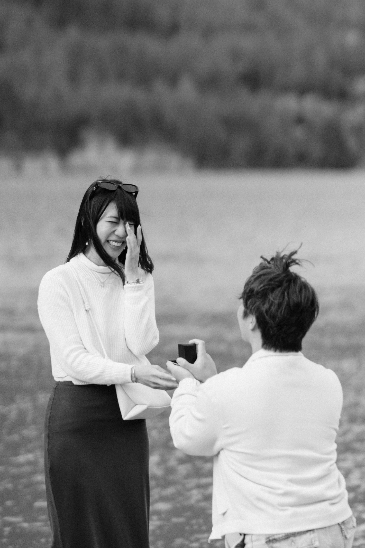 Two people practice martial arts sparring moves outdoors in white and black outfits.