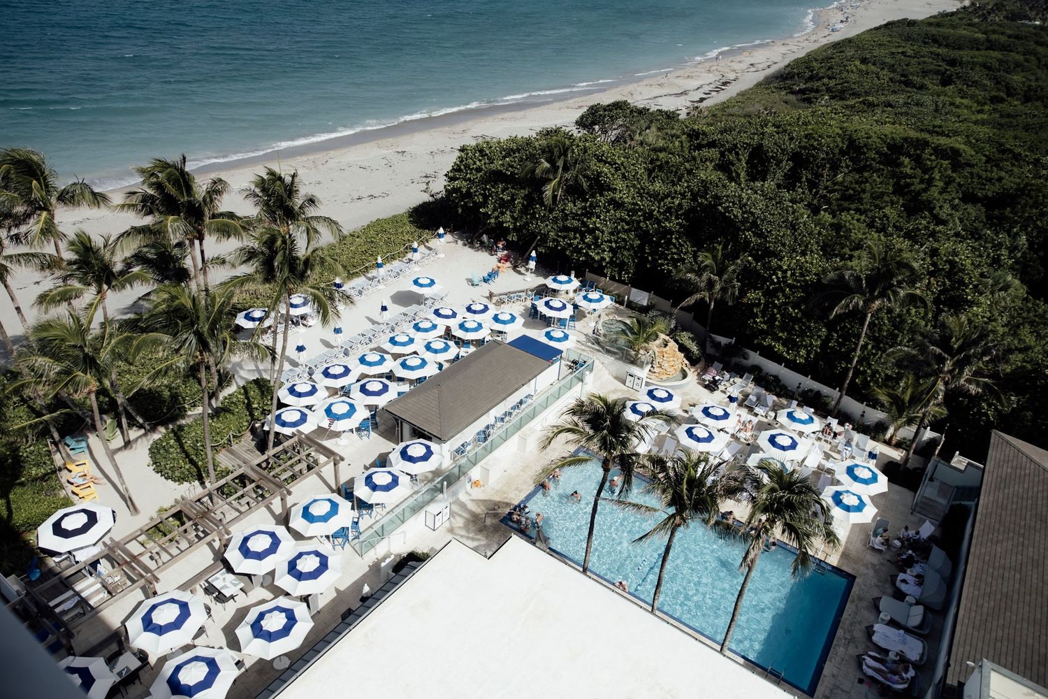 Aerial view of a luxury oceanfront resort with multiple pools, palm trees, and pristine beach access.