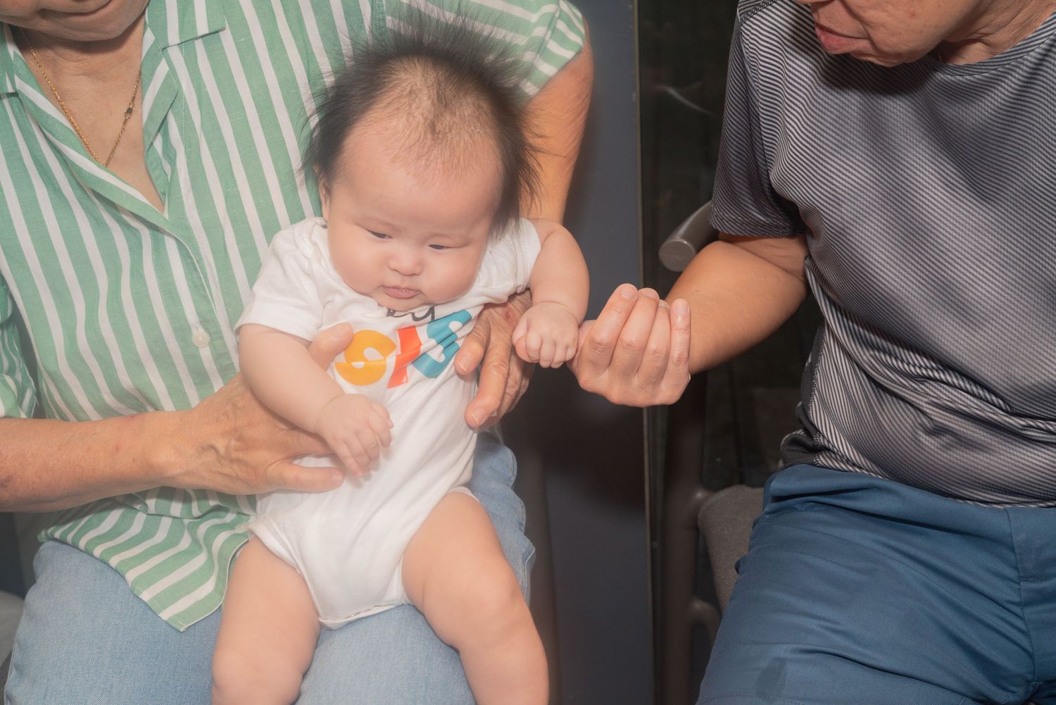 A collage strip showing an infant held by an adult in casual clothing against a green striped background.