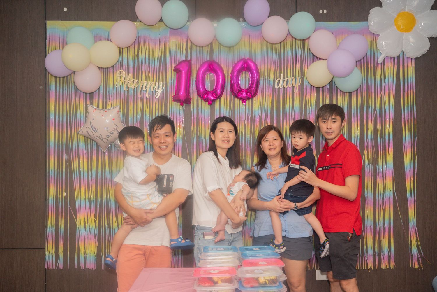 A colorful birthday party celebration with balloons and streamers featuring people gathered around a decorated table.