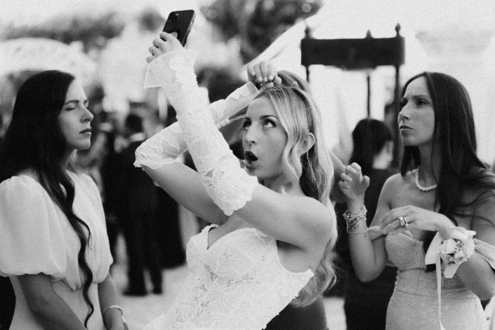 Group celebrates at an outdoor event as people dance and raise their hands in a black and white photograph.