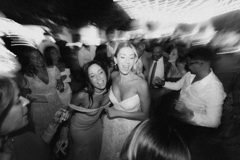 Guests dance and celebrate at a lively wedding reception in black and white photography.