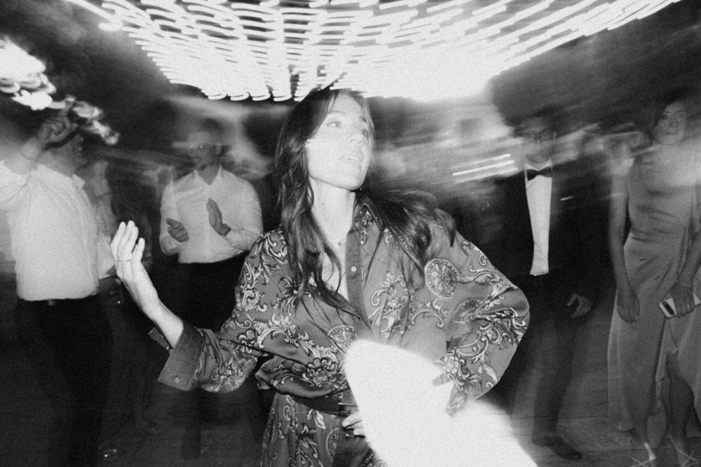 A blurred black and white dance floor scene shows people moving energetically at what appears to be a party or celebration.