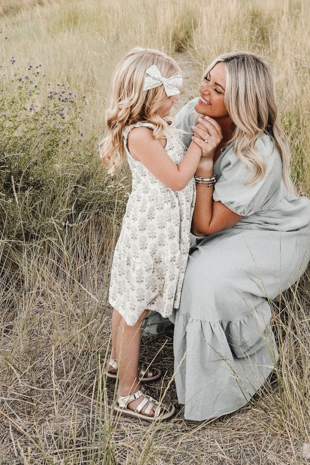 Mother and child share loving moments in tall grass field.