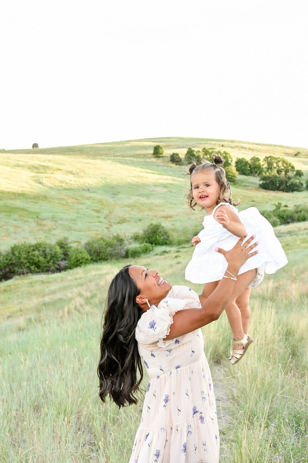 Mother and baby playing together in sunlit meadow.