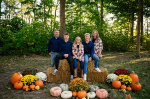 Fall family photos with pumpkins, hay bales, and mums creating a cozy autumn setting.