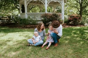 Family enjoying time together on grassy lawn near white gazebo on sunny day.