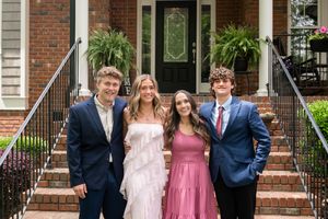 Formal group photo in front of brick house with formal attire and spring dresses.